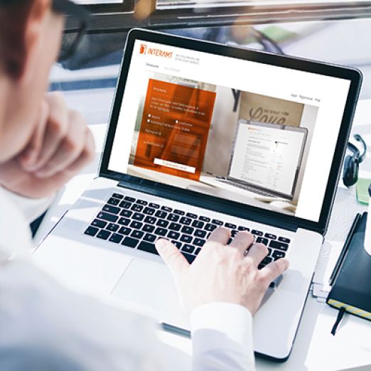 Mann blickt auf Laptop und hat INTERAMT-Website geöffnet