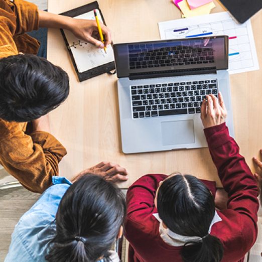 Foto: Mehrere Schüler arbeiten an einem Laptop