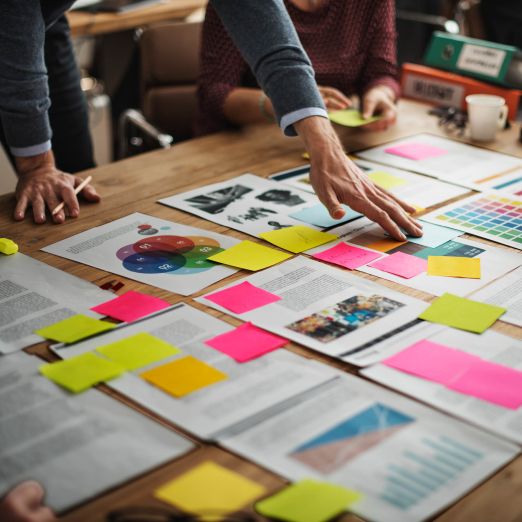 Arbeit mit ausgedruckten Papieren und Post-its auf einem Tisch