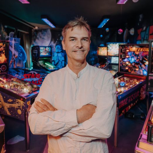 Arne Hennes steht vor mehreren Flipperautomaten